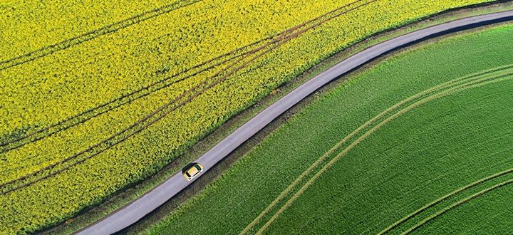 A car driving on a road in fields (photo)
