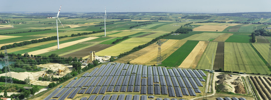 Aerial view over fiels with solar panels and wind mills (photo)